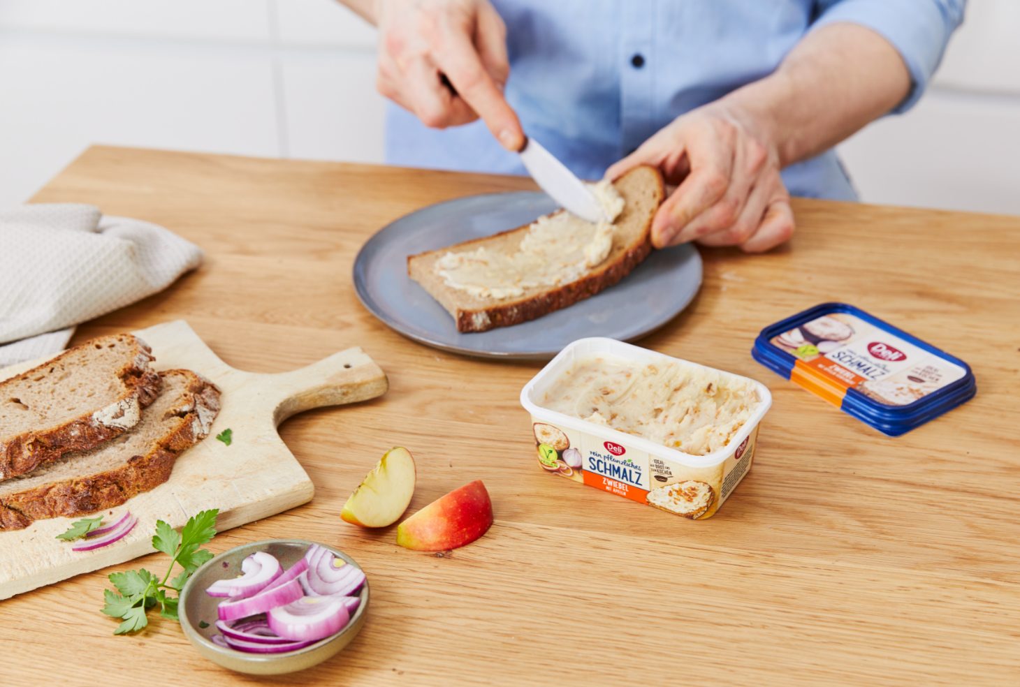 Eine Person bestreicht eine Brotscheibe mit Deli Reform Schmalz.